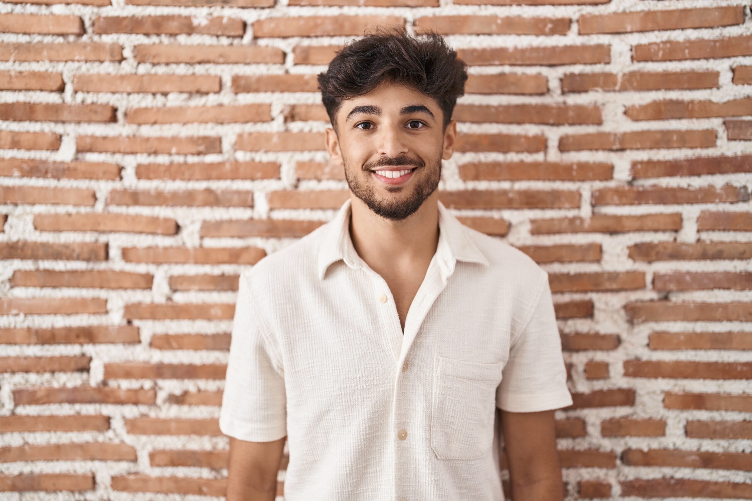 arab man with beard standing bricks wall background with happy cool smile face lucky person scaled